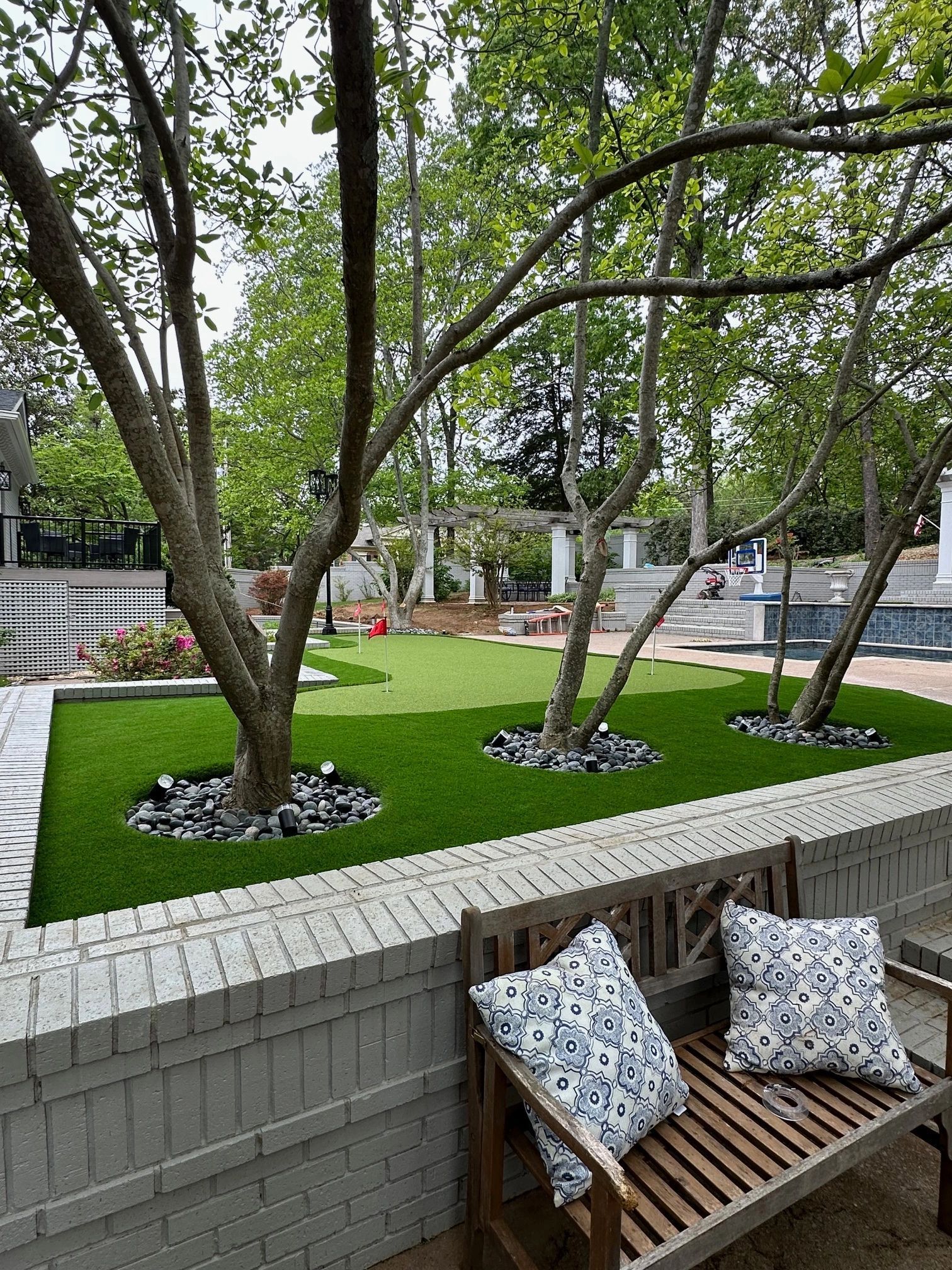 Backyard putting green with mature trees set into stone rings